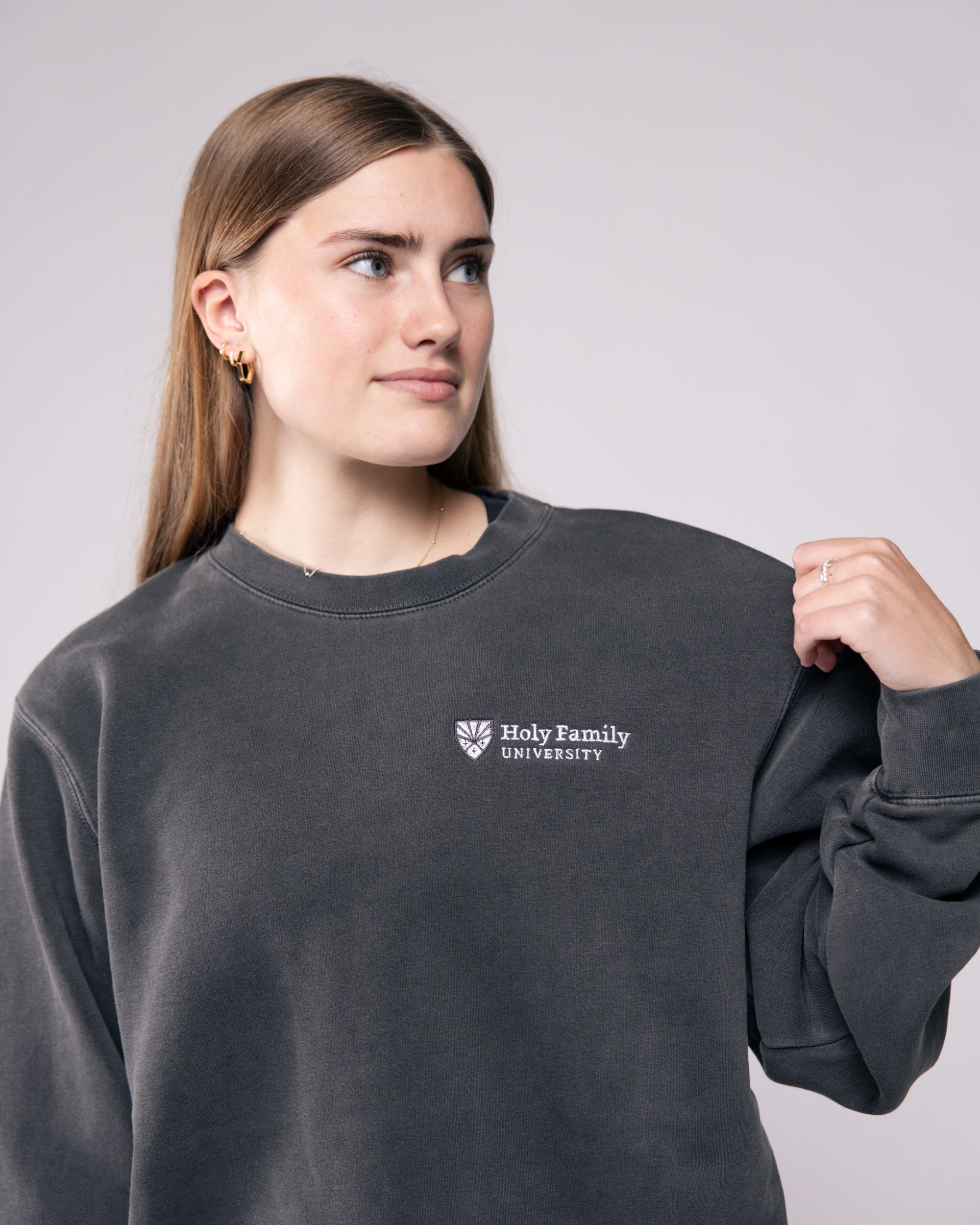 Person wearing a dark gray sweatshirt with 'Holy Family University' logo on a light gray background